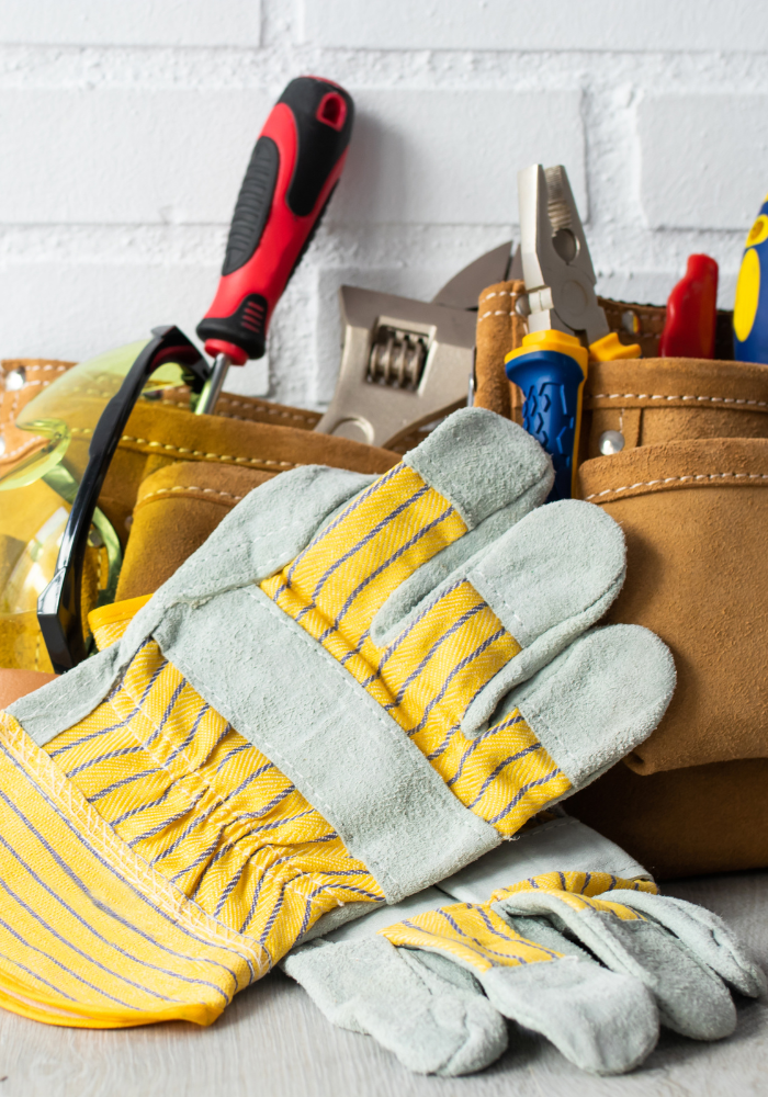 A pair of gloves sitting on top of a tool belt filled with tools.