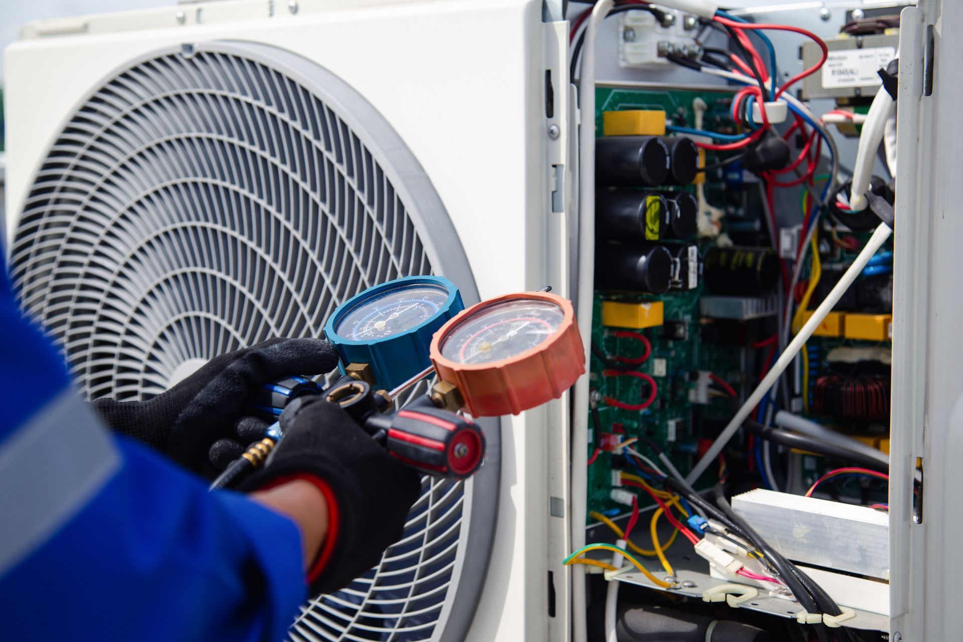 Close-up of air con technicians in blue uniforms, servicing a unit.