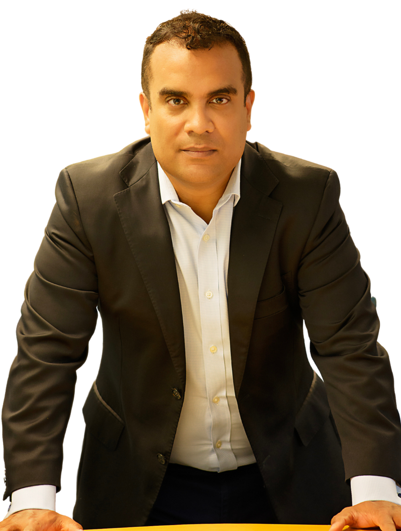 A man in a suit and white shirt is leaning on a table