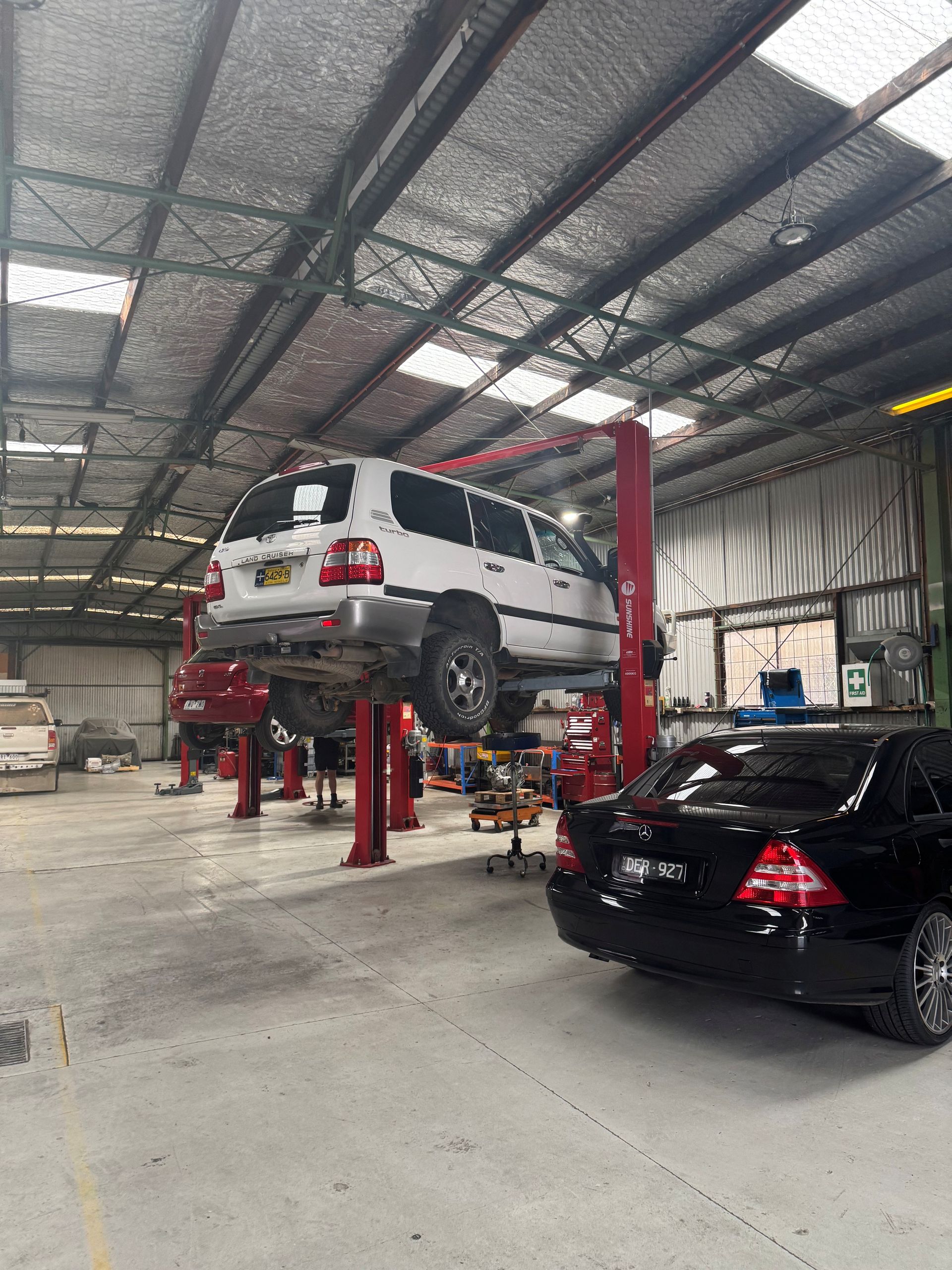 A white truck being lifted and black car on ground — Burko Transmissions in Shepparton, VIC