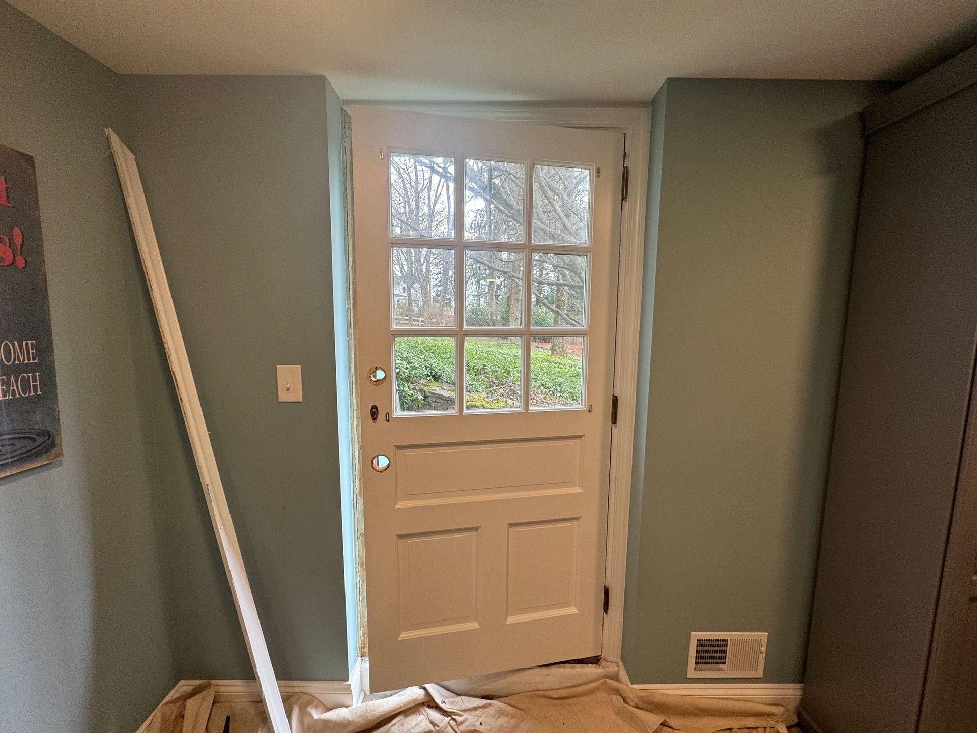 White door with glass panes, framed in blue walls. Trim pieces leaning against the wall.