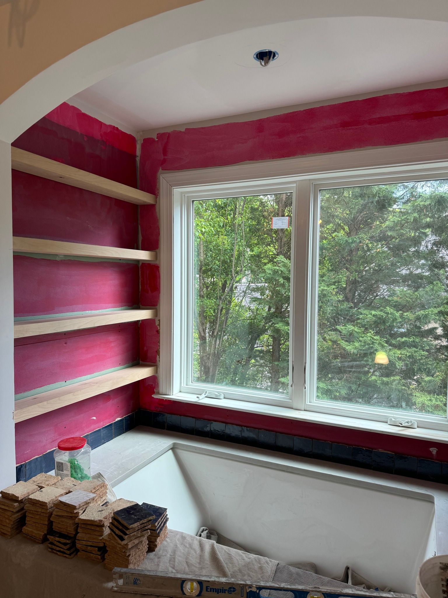 Room under construction, featuring shelves, window, and red wall with white trim.