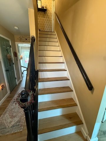 Staircase with white steps, black railings, and beige walls in a narrow hallway.
