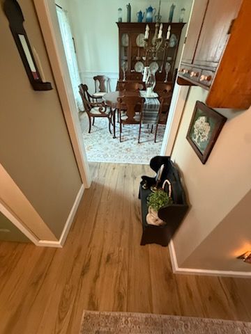 Hallway with wood floors leading to a dining room and china cabinet, with a small basket by the wall.