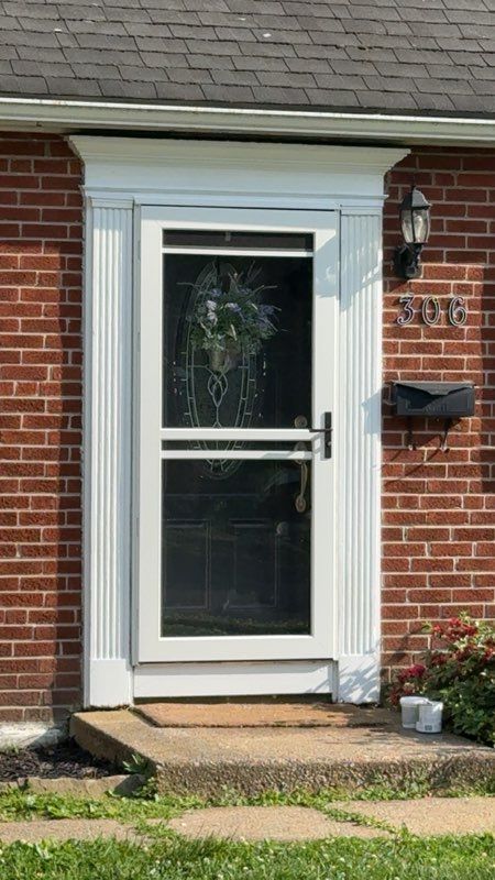 White front door with glass panel on a brick house, framed by white trim and a small stoop.