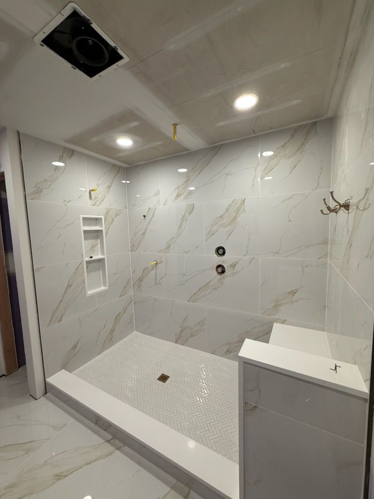 Modern white tiled walk-in shower with recessed lights, built-in niche, and bench seat