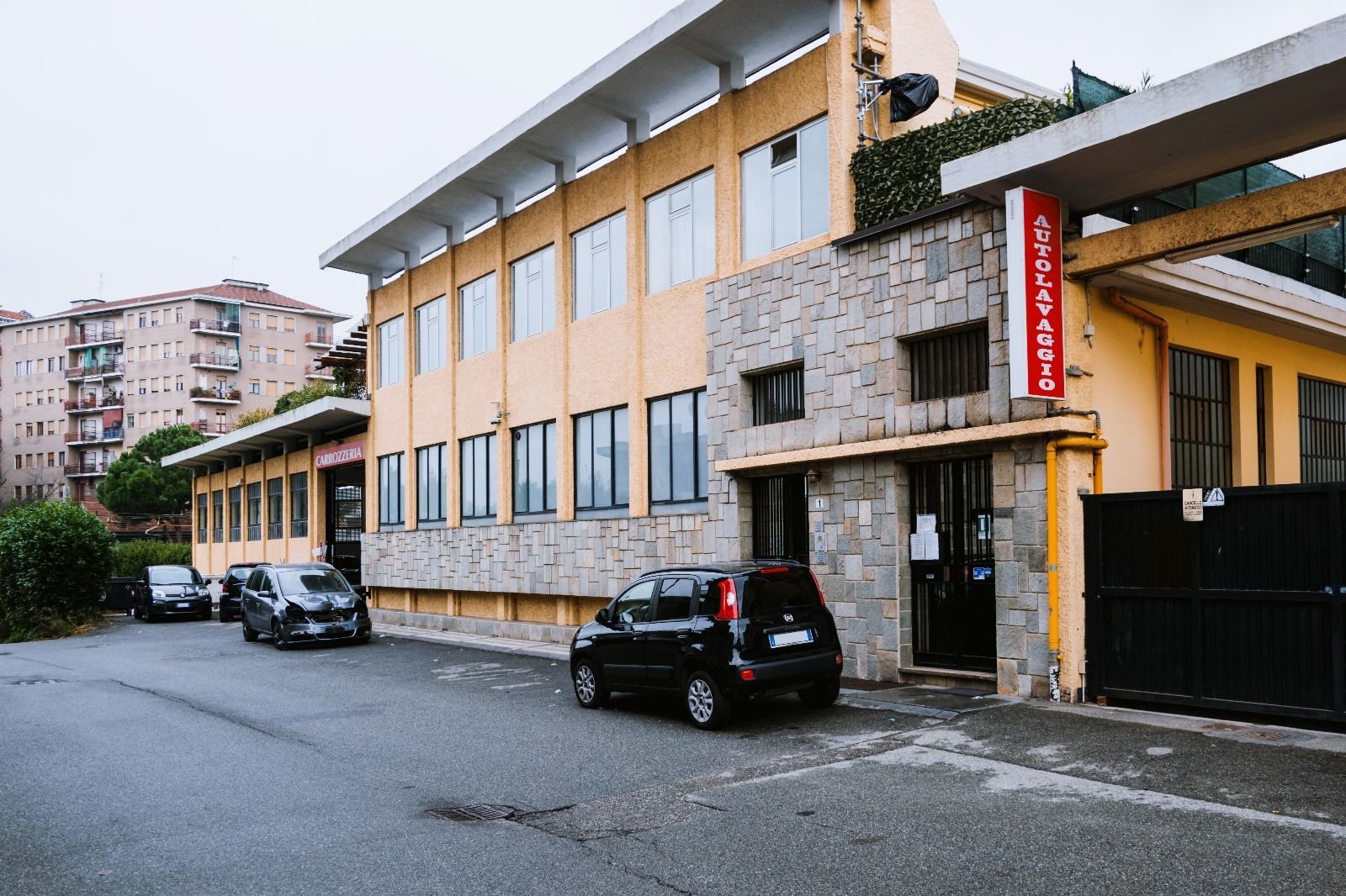 Un edificio con auto parcheggiate di fronte e un cartello che dice emergenza
