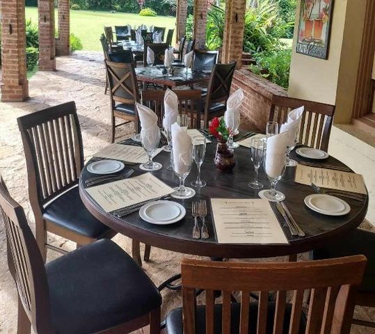 Outdoor restaurant table set for dining: black leather chairs, white napkins, and menus.