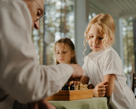 People gathered around a chessboard, with one person moving a piece while others watch closely.