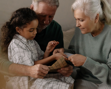Family gathered on a couch, examining a small woven object together