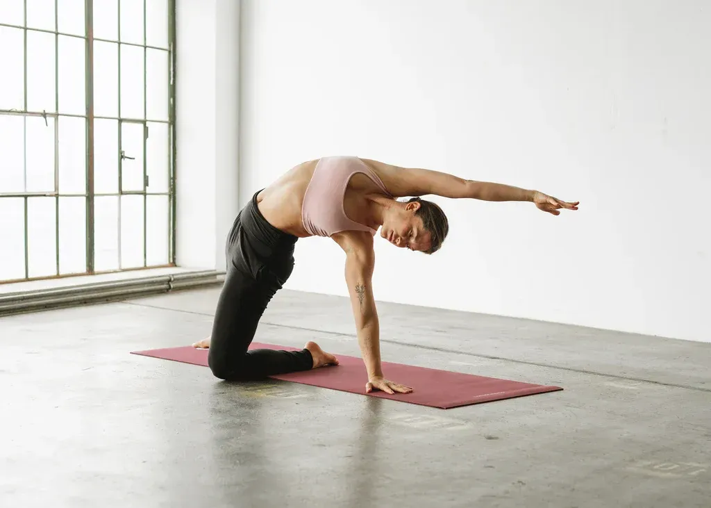 A woman is doing a yoga pose on a mat in a room.