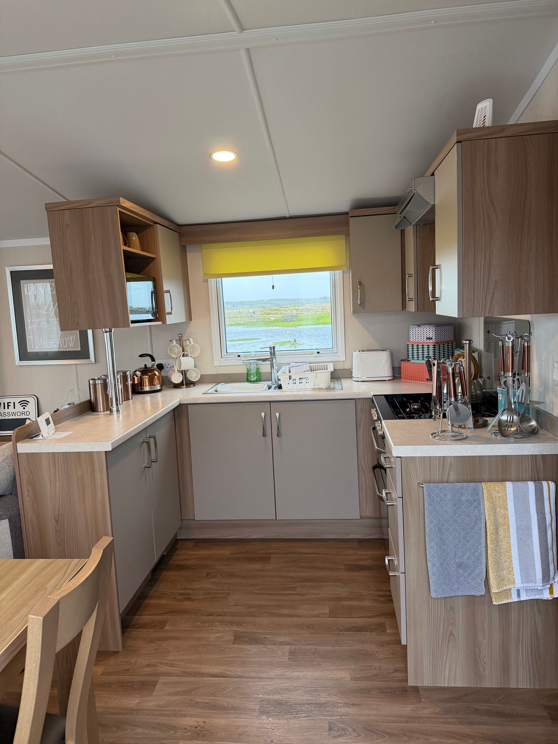 Compact kitchen with wood cabinets, white counters, and a bright window over the sink.