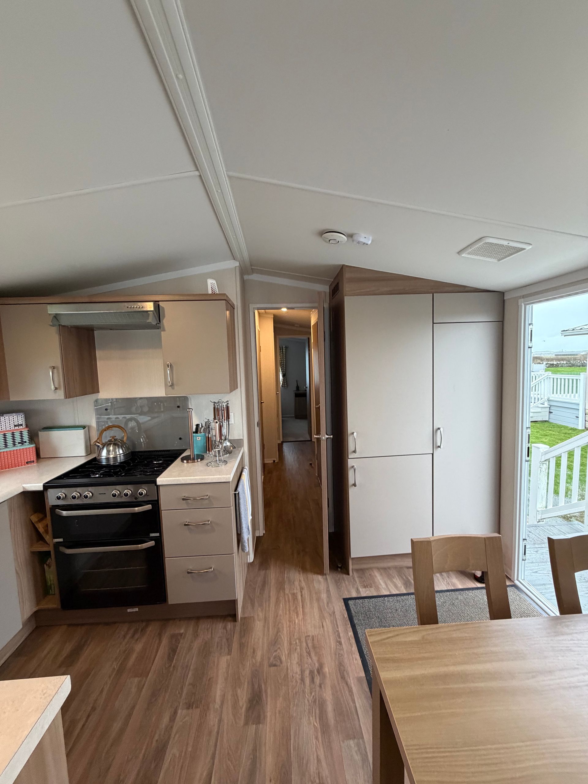 Compact kitchen and dining area in a small home, with wood floors, white cabinets, and a table by a bright window.