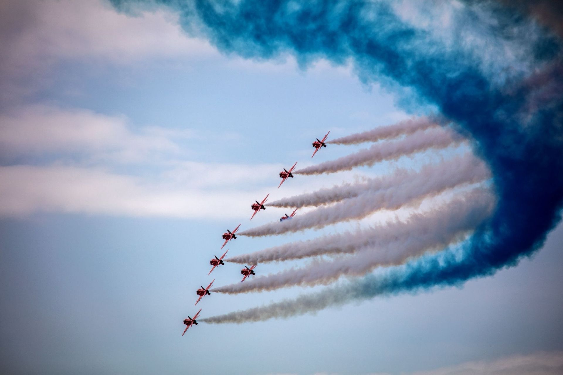 Jet formation leaving white smoke trails in a blue sky, curving in a tight arc