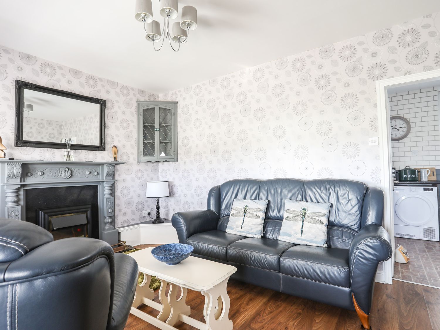 Living room with blue sofas, fireplace, coffee table, and patterned wallpaper