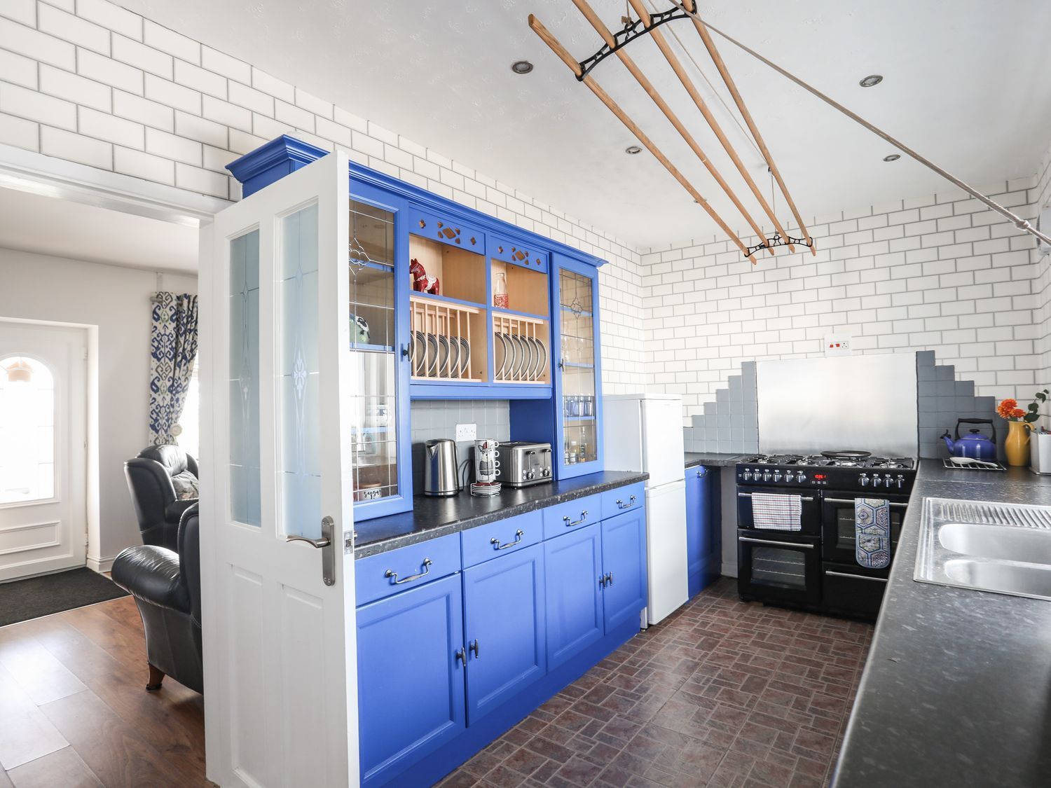 Bright kitchen with blue cabinets, white brick walls, and a stove in the back corner.