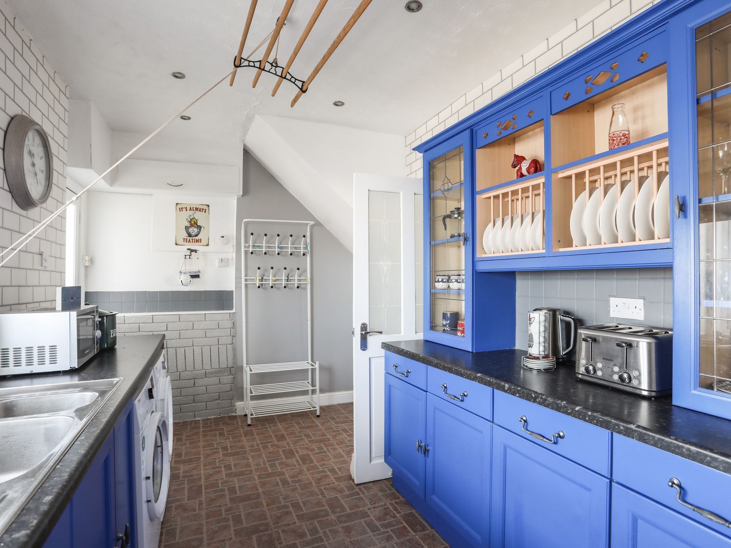 Bright blue kitchen with white cabinets, tiled floor, and a stainless steel coffee maker on the counter.