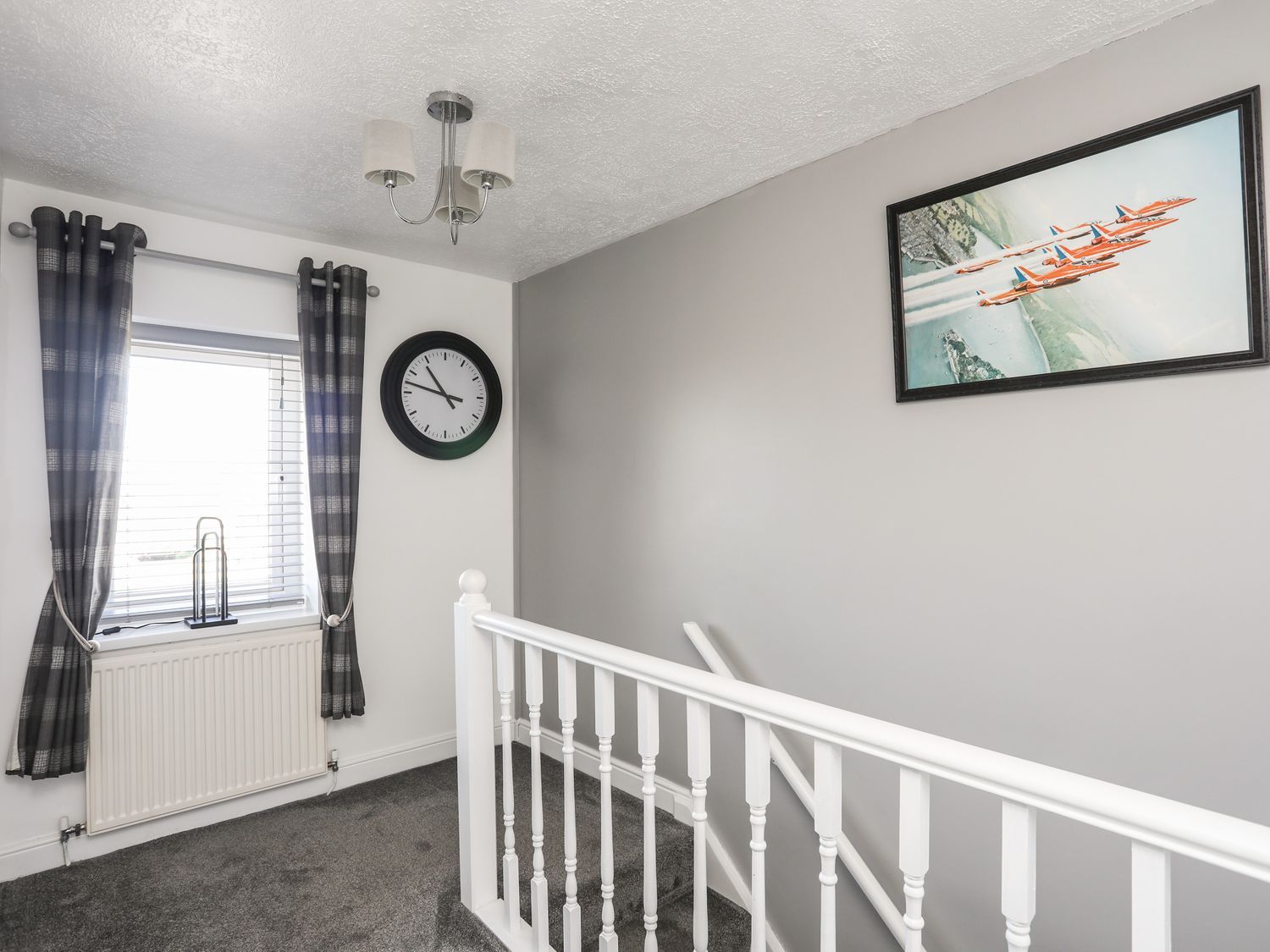 Bright bedroom corner with gray walls, white crib rail, window with curtains, clock, and framed fish art