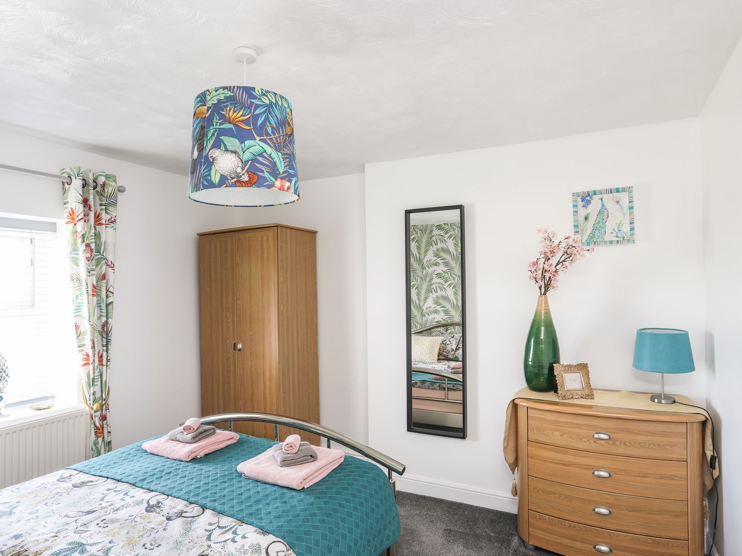 Bright bedroom with bed, wardrobe, dresser, and blue lampshade on white walls