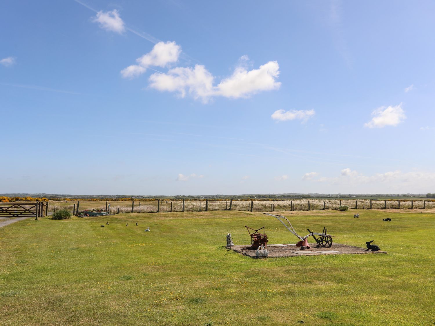 Open grassy field under a blue sky with a few small objects near the center