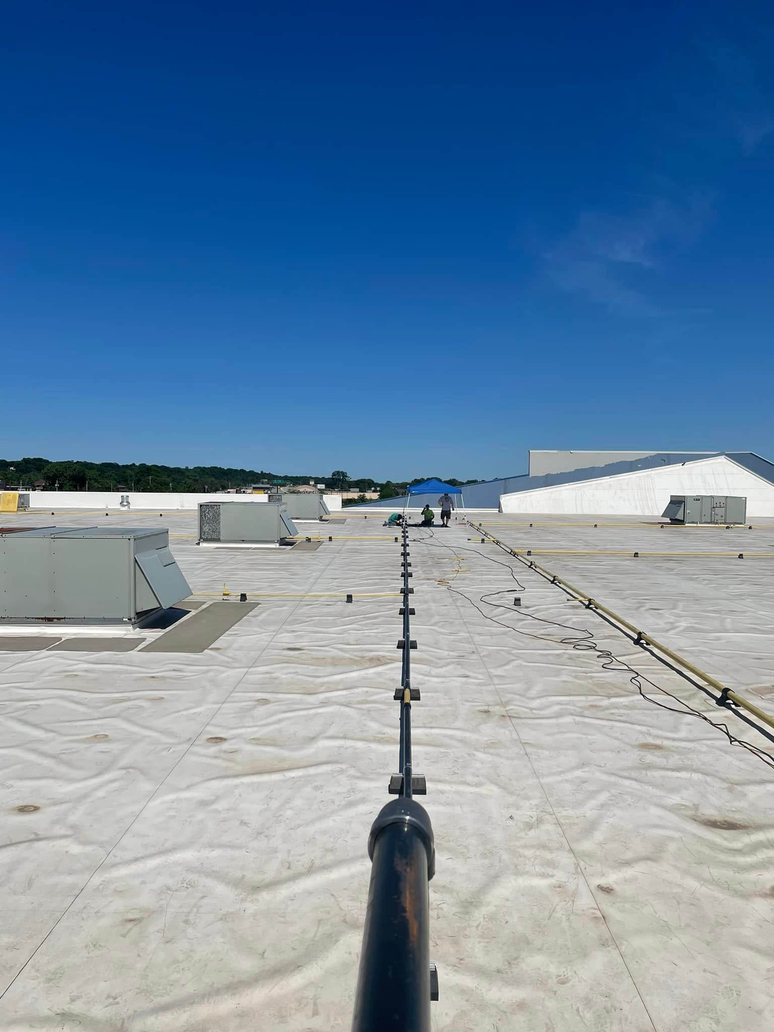 A person is standing on a roof with a pole in the foreground