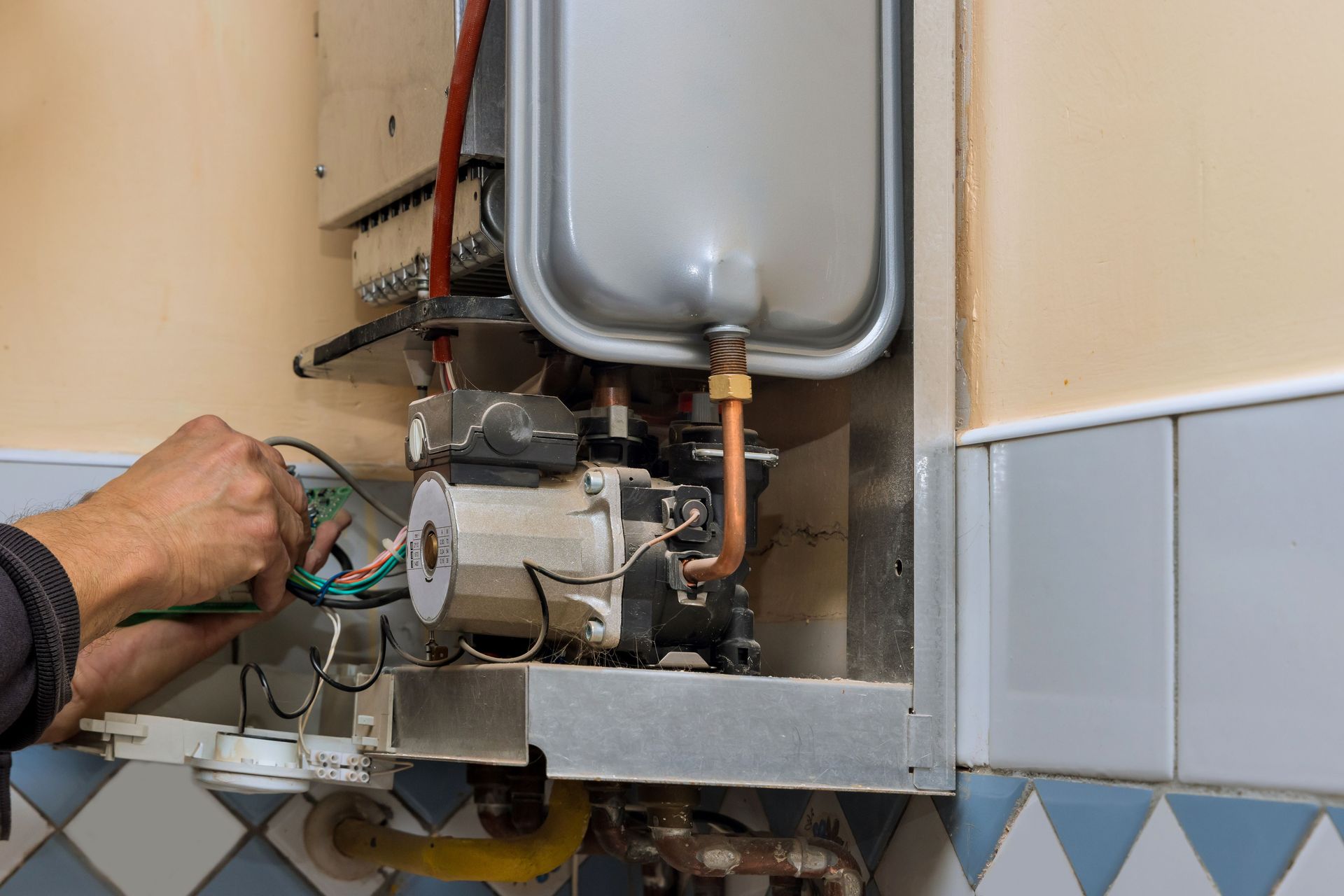 A man is fixing a boiler in a kitchen.