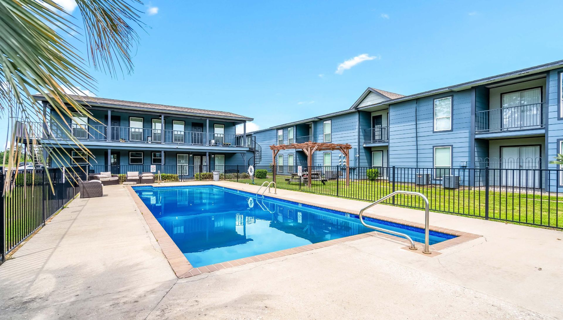 Apartment complex courtyard with a blue swimming pool and surrounding walkway and buildings