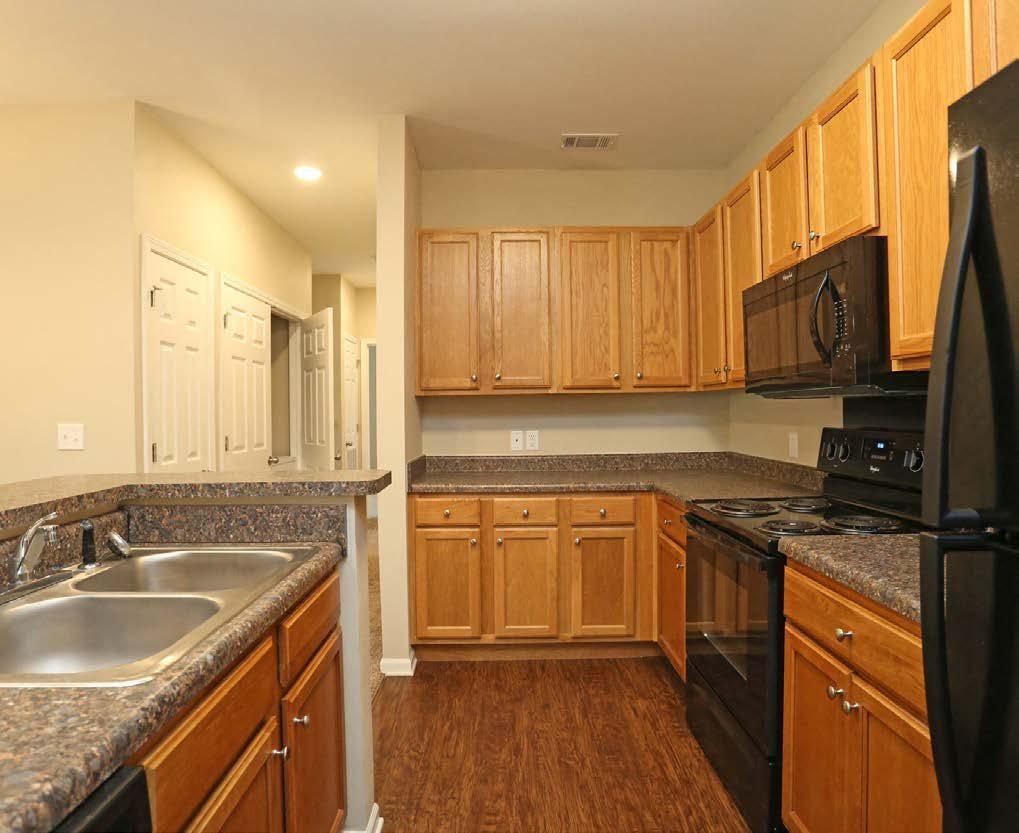 Modern kitchen with wood cabinets, black appliances, granite counters, and double sink