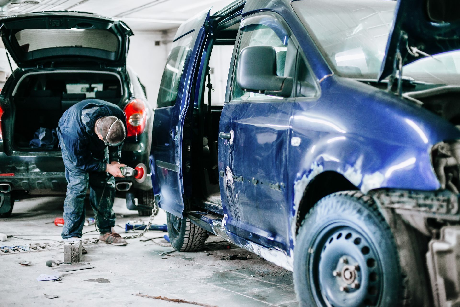 a man is working on a blue van in a garage .