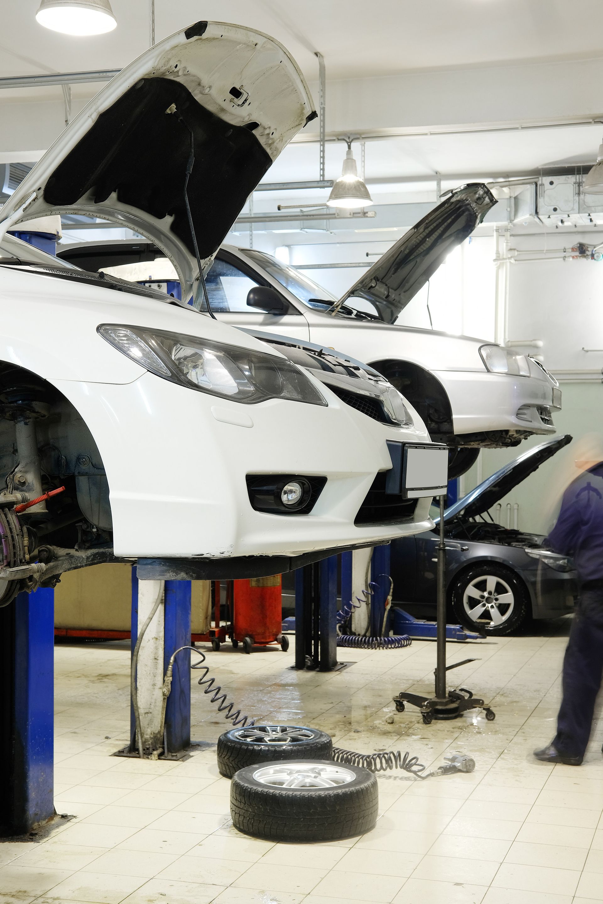 a white car is sitting on a lift in a garage with its hood open .