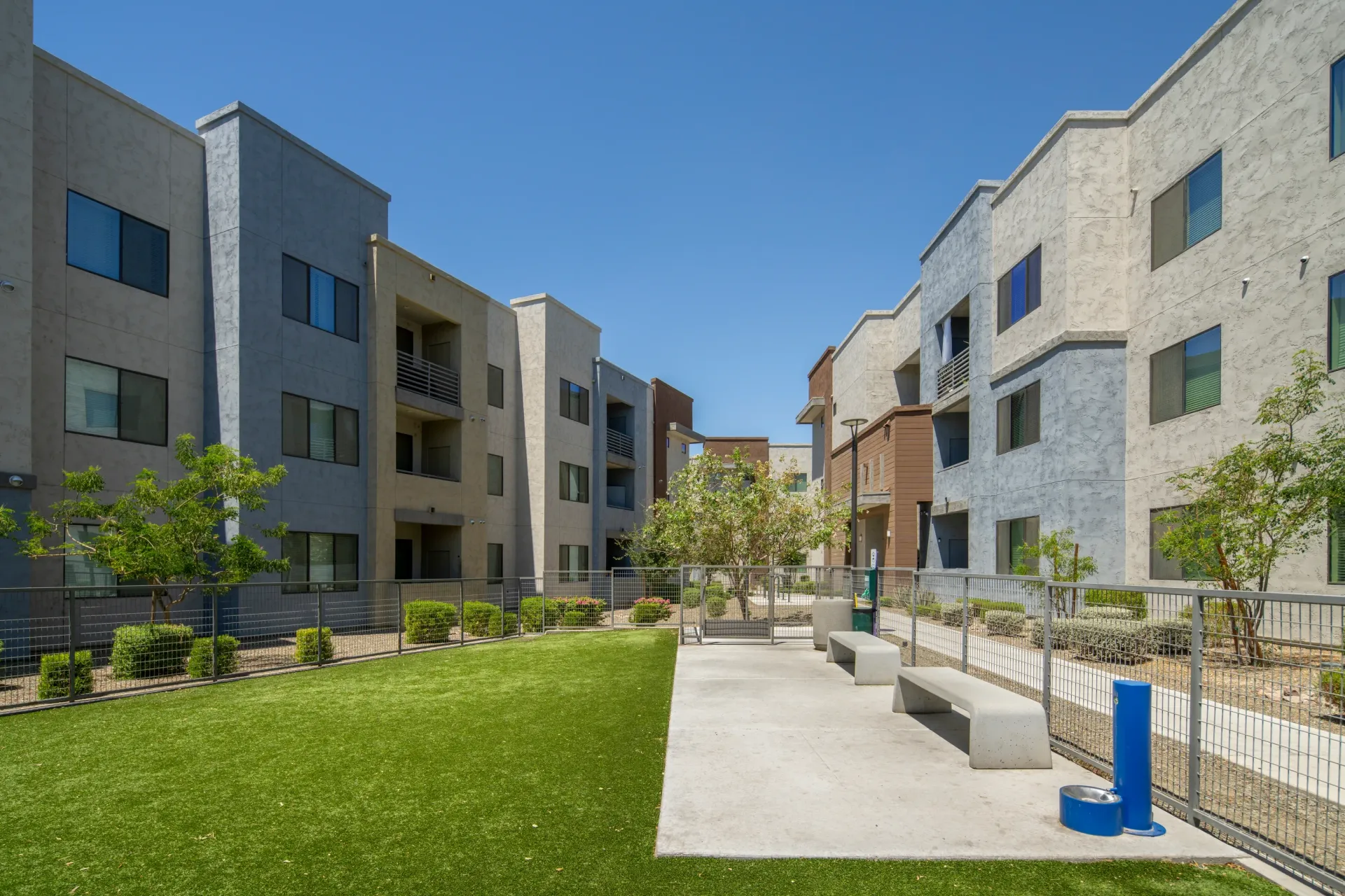 Outdoor courtyard with artificial turf, seating, and dog amenities at Parc Lofts in Tolleson, AZ.