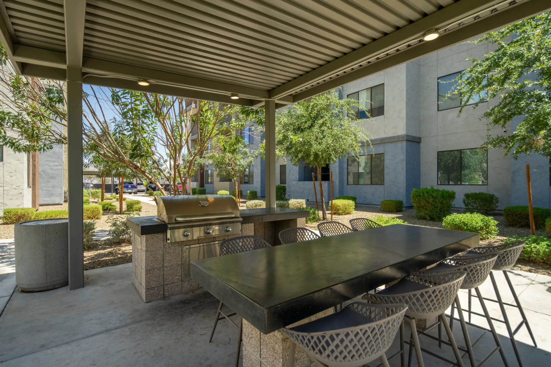 Outdoor grilling area with a built-in grill and a long bar with stools at Parc Lofts in Tolleson, AZ.