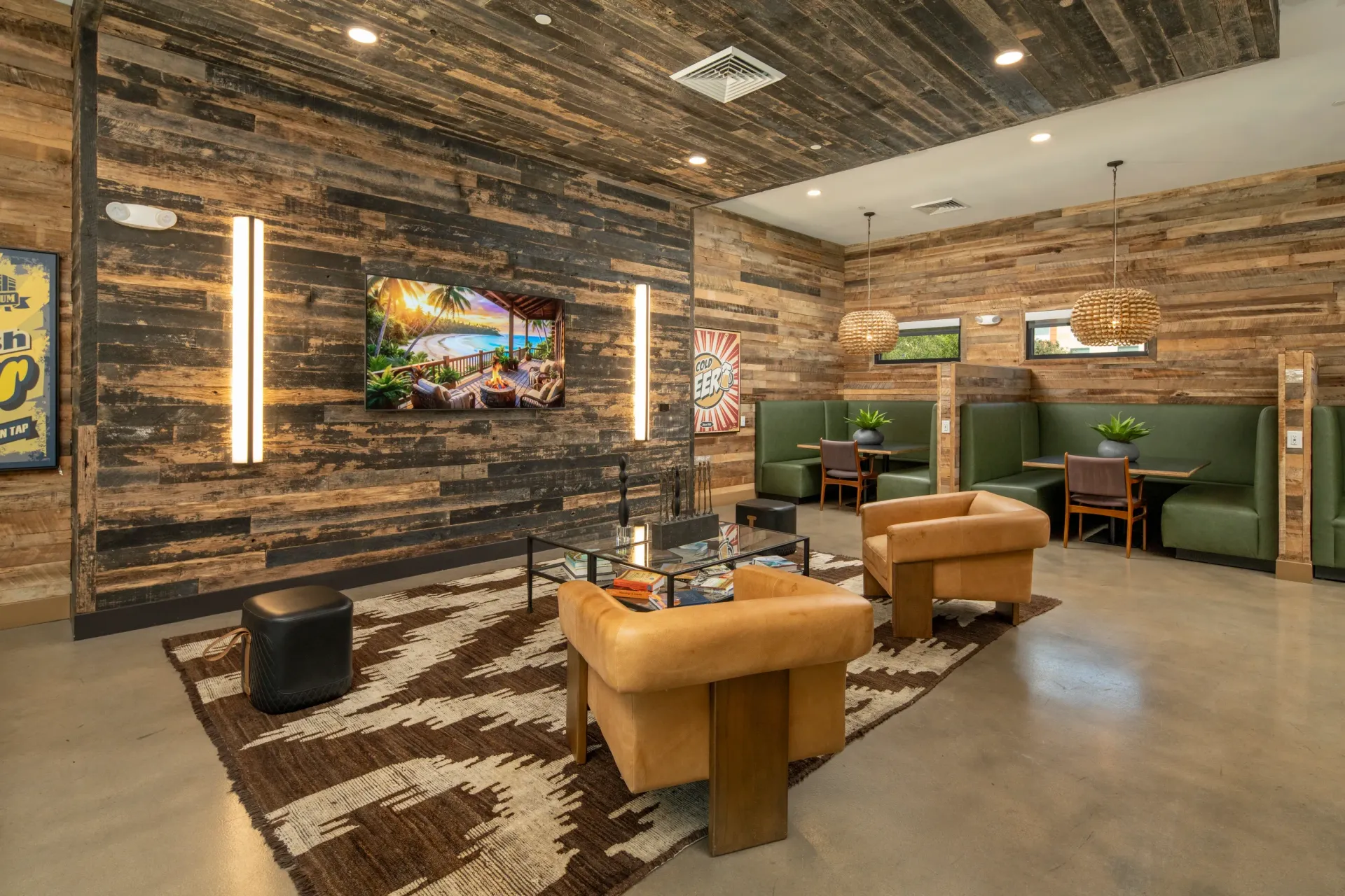 Lounge area with wood-paneled walls, comfortable seating, and a TV displaying a tropical scene at Parc Lofts in Tolleson, AZ.