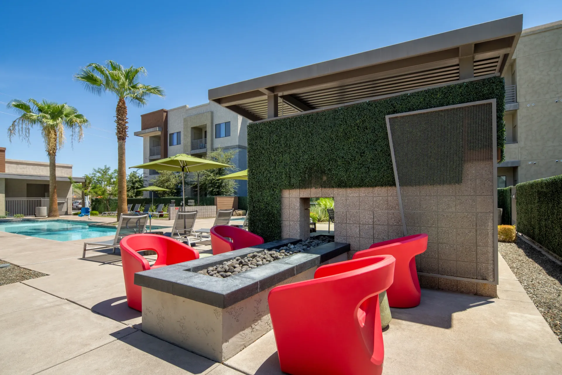Modern outdoor seating area with a fire pit, lounge chairs and pool at Parc Lofts in Tolleson, AZ.