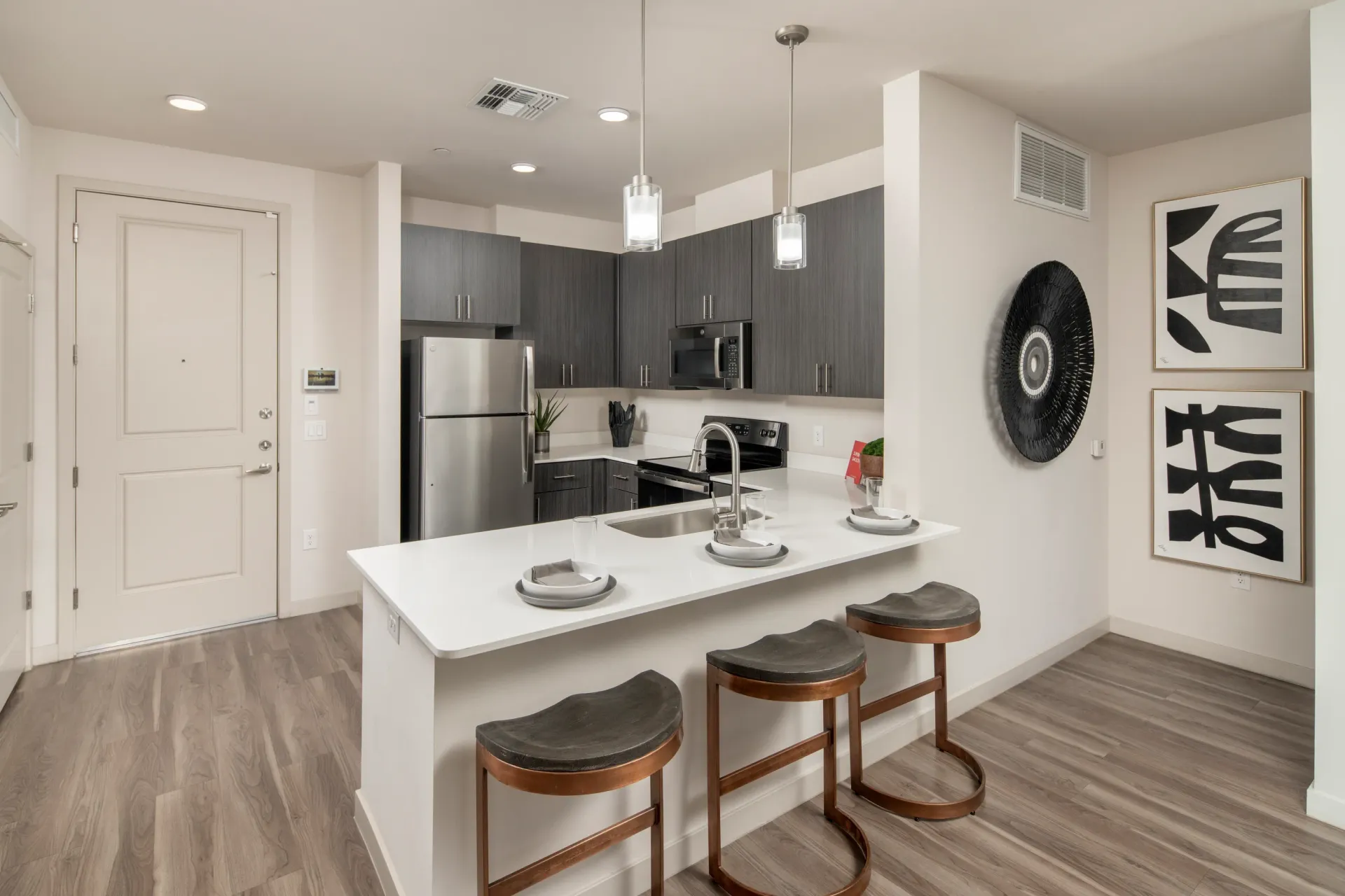 Modern kitchen with stainless steel appliances, dark cabinetry, and a white island with bar stools at Parc Lofts in Tolleson, AZ.
