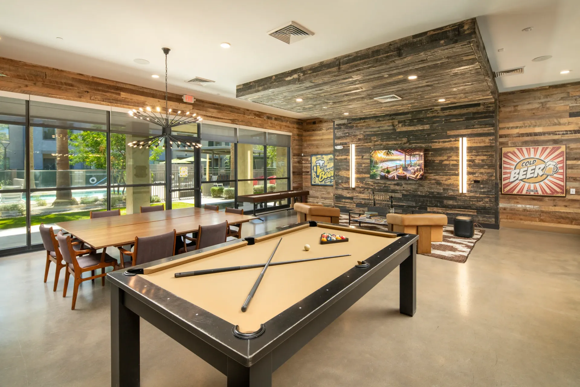 Community lounge with pool table, dining table, and TV at Parc Lofts in Tolleson, AZ.