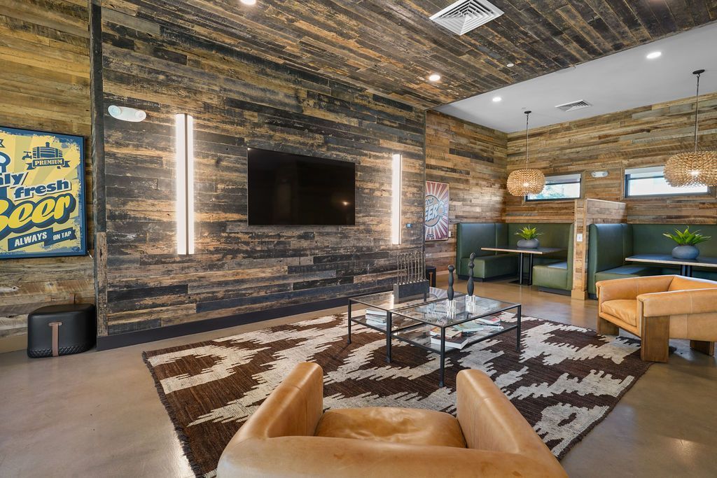Parc Lofts community lounge with a wall-mounted TV, wood-paneled walls, and cozy seating.