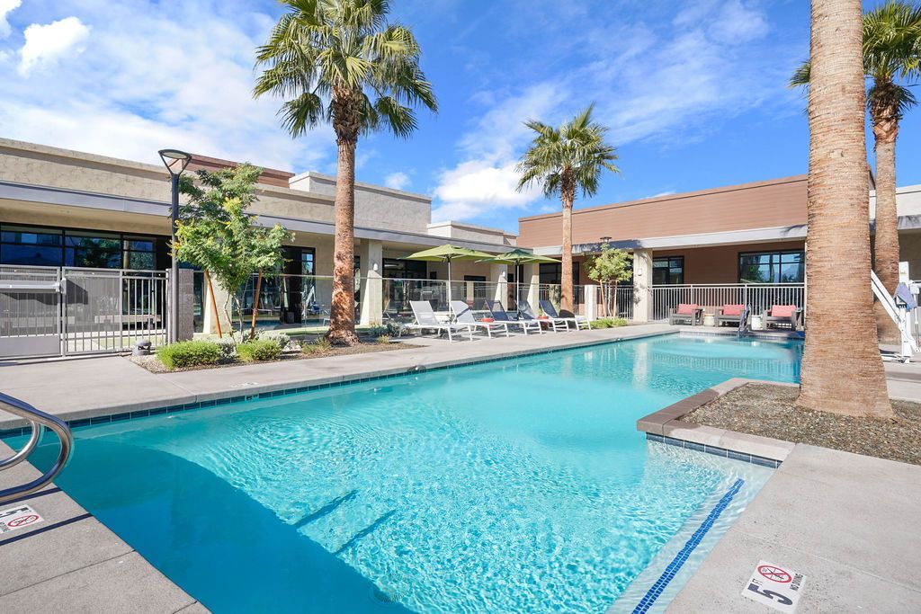 Parc Lofts pool area at a modern apartment community with sun loungers and palm trees.