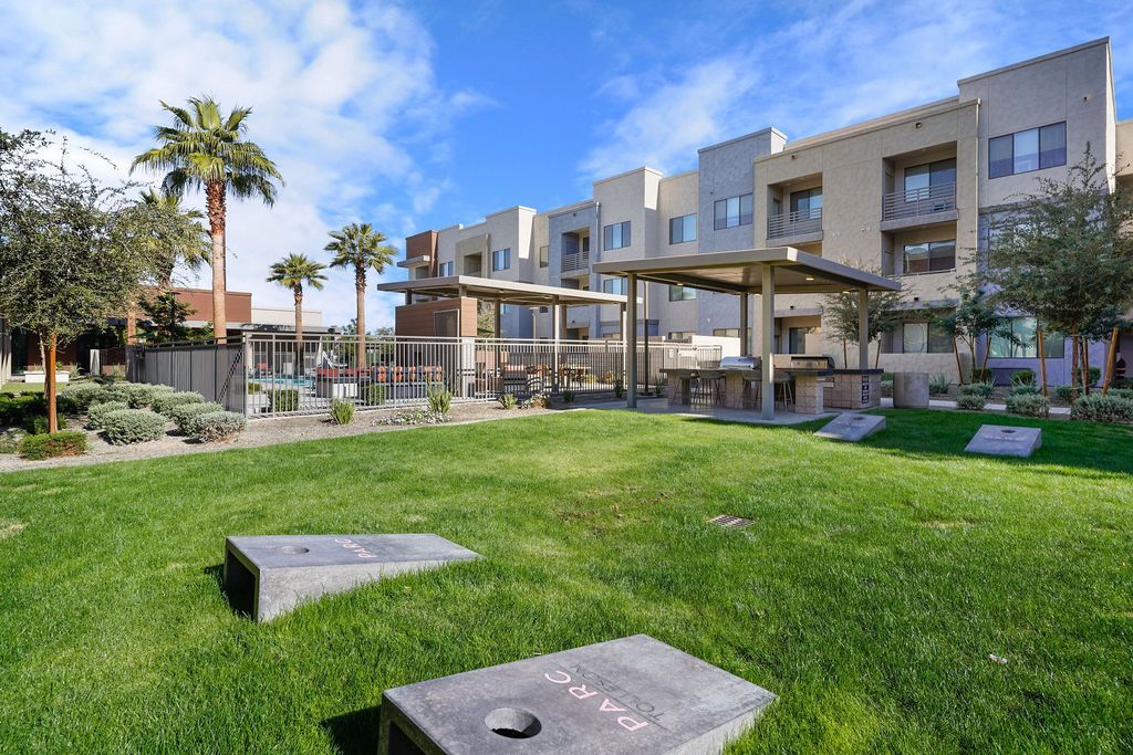 Parc Lofts  view of a modern apartment community courtyard with lawn and grilling area.