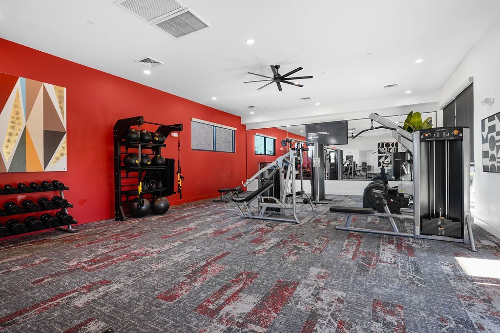 Parc Lofts Fitness center with red accent wall, free weights, and multi-station gym equipment.