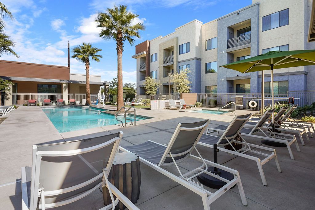 Parc Lofts apartment community pool with lounge chairs and palm trees.