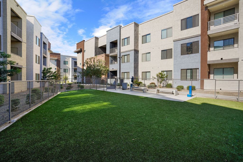 Parc Lofts  Courtyard with artificial turf, benches, and a fence-lined walkway between modern apartment buildings.