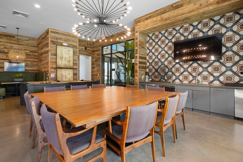 Parc Lofts community lounge with a large wooden table, TV, and geometric wall accents.