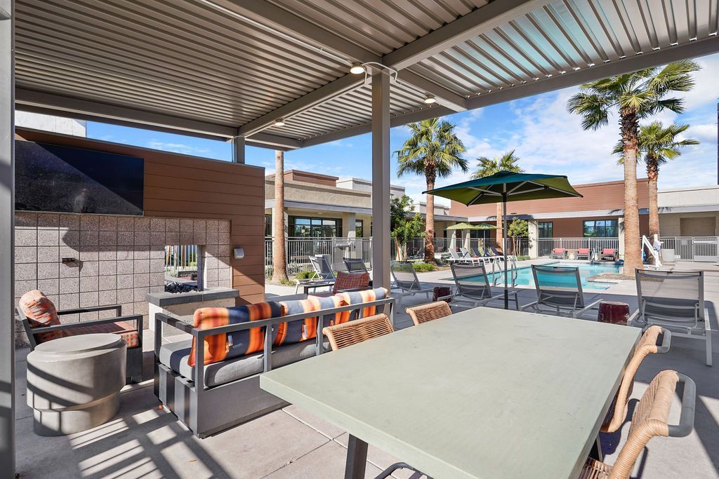 Parc Lofts pool area with lounge seating, umbrellas, and palm trees under a covered patio.