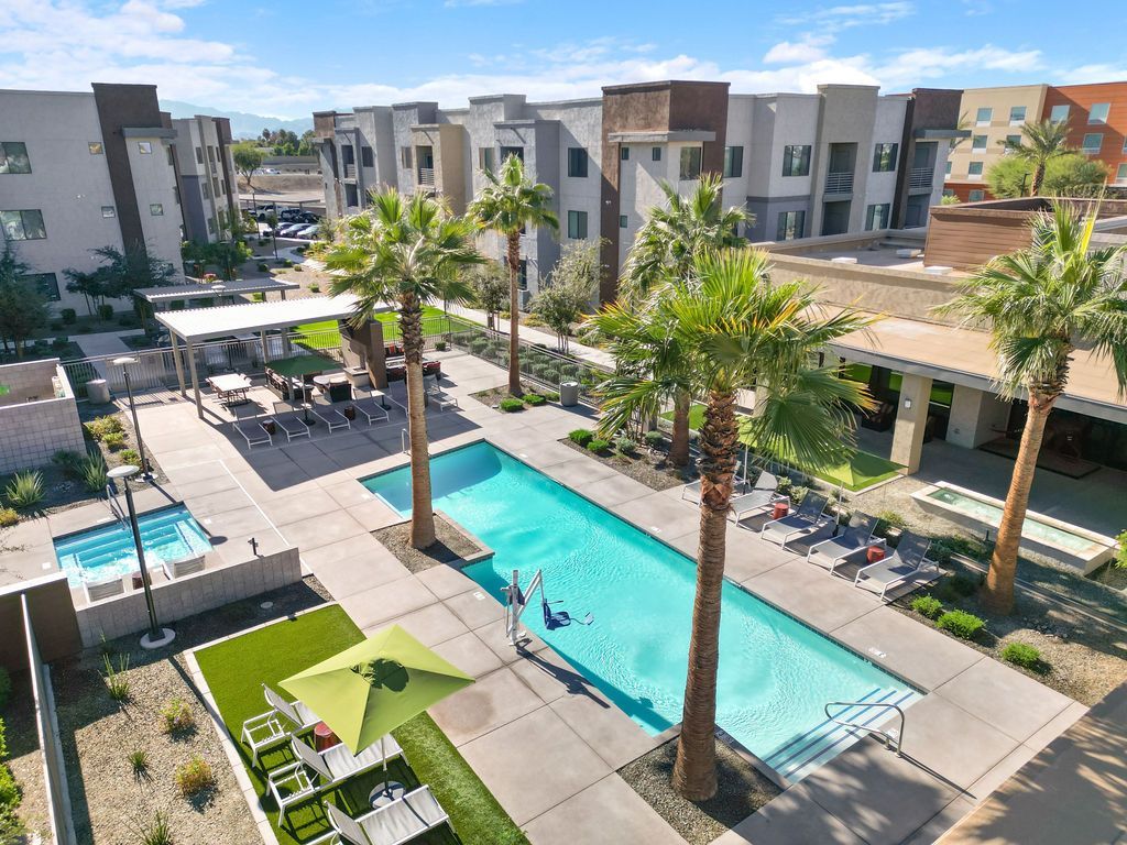 Parc Lofts view of a resort-style apartment pool with palm trees and lounge chairs.
