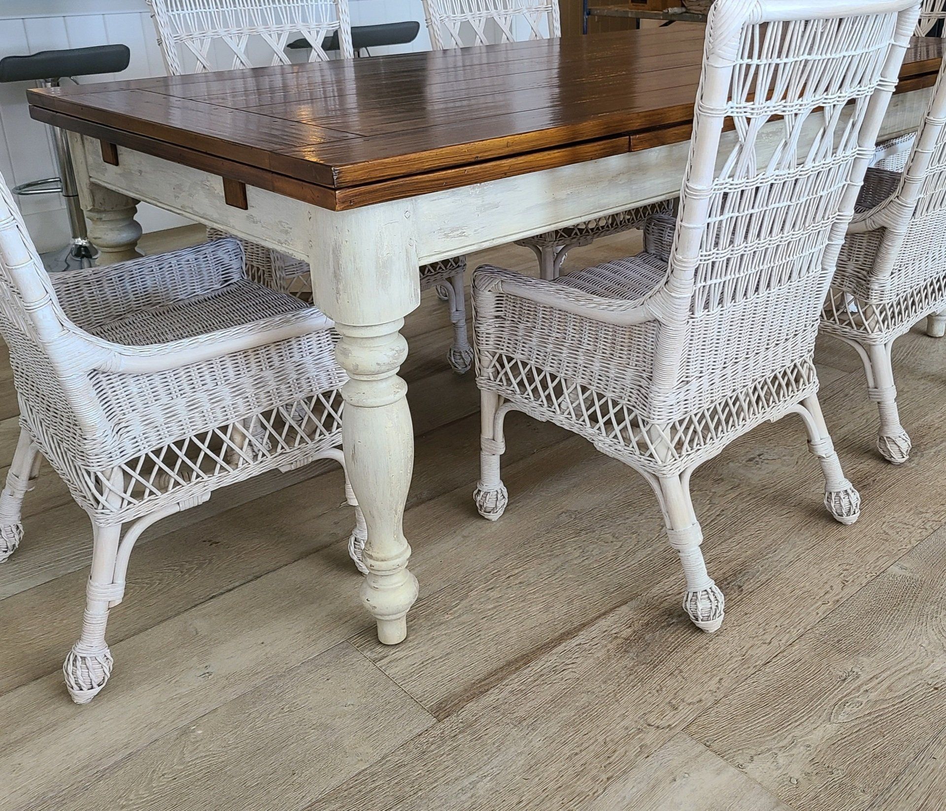 Wooden table with white wicker chairs on a light-colored floor.