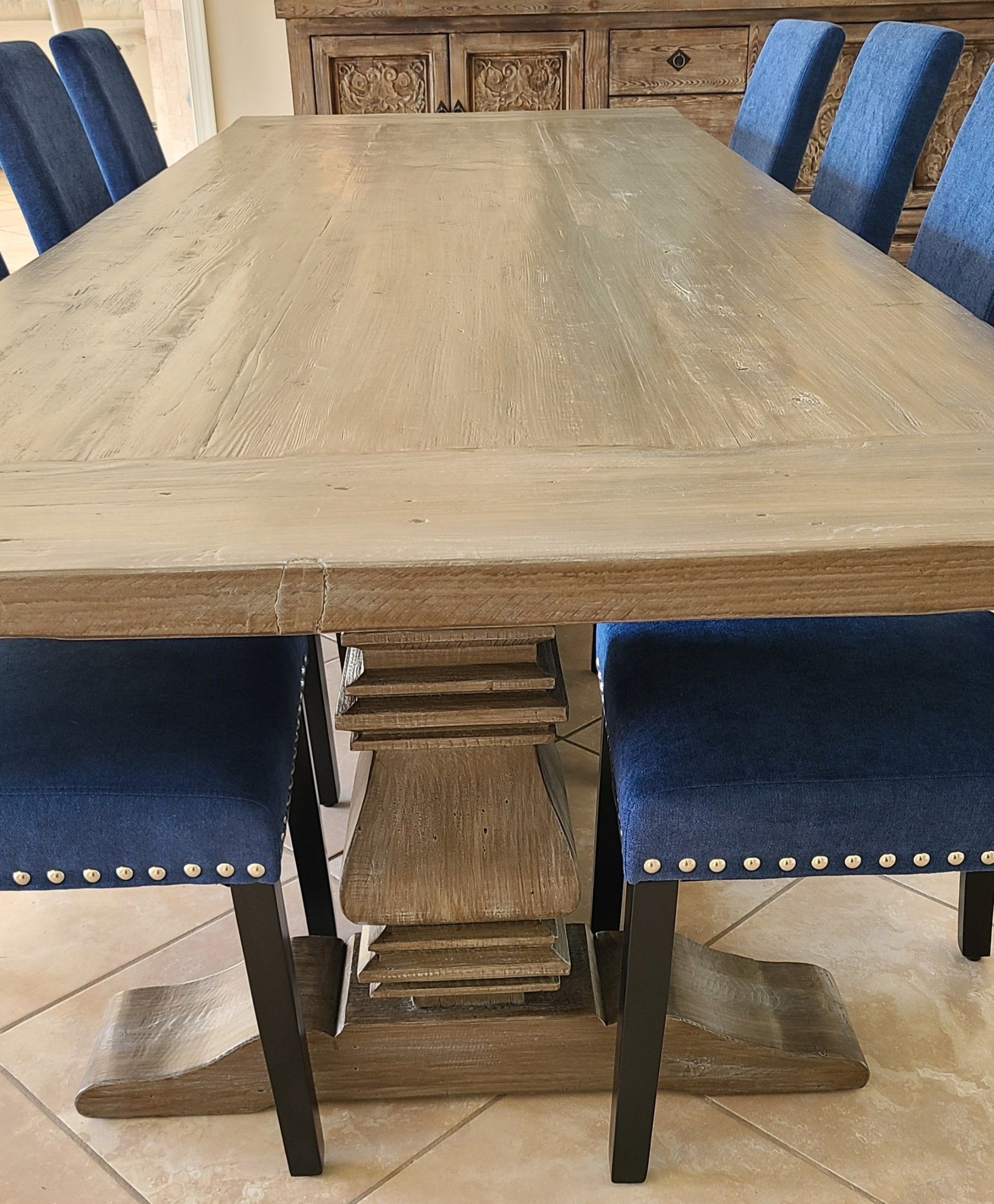 Wooden dining table with blue upholstered chairs in a room.