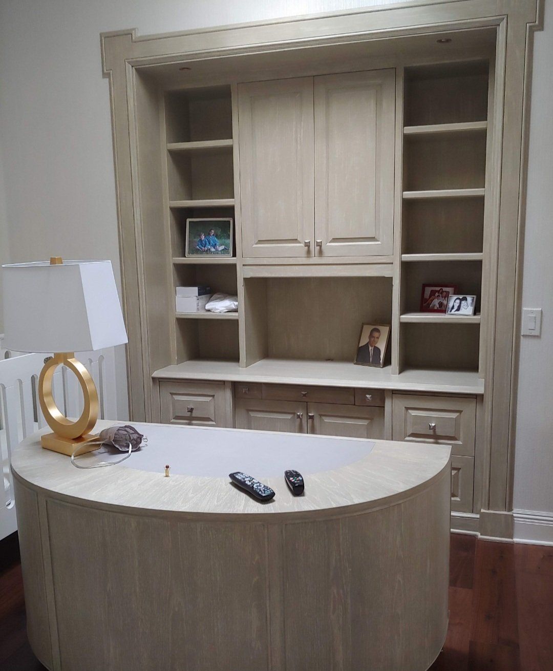 Beige home office with curved desk and built-in shelving unit.
