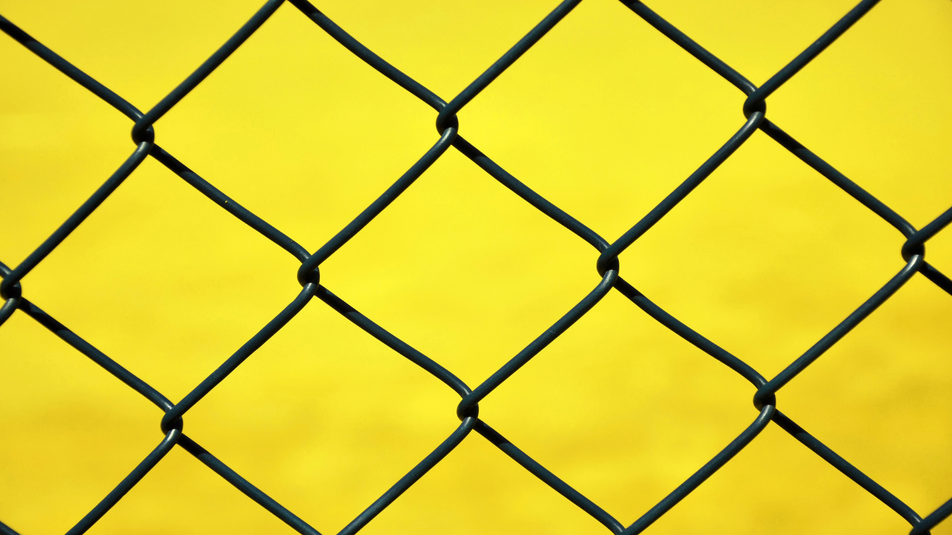 Black chain-link fence against a bright yellow background.