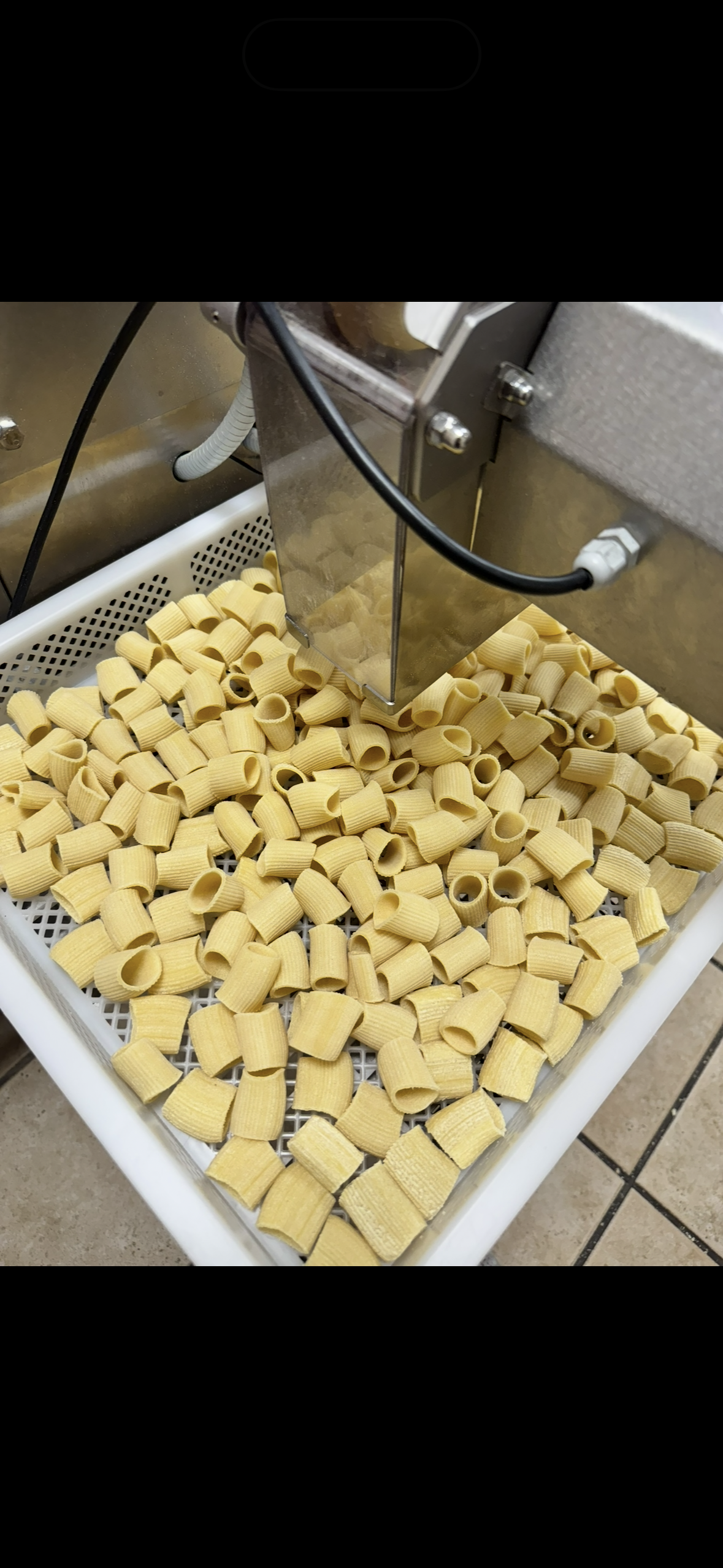 Tray of cubed dough pieces under a metal slicer in a bakery setting